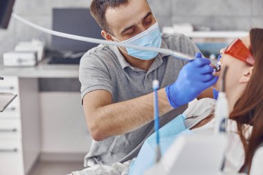 Kendine güvenen dişçi modern ışık stamotoloji dolabında matkap kullanıyor.