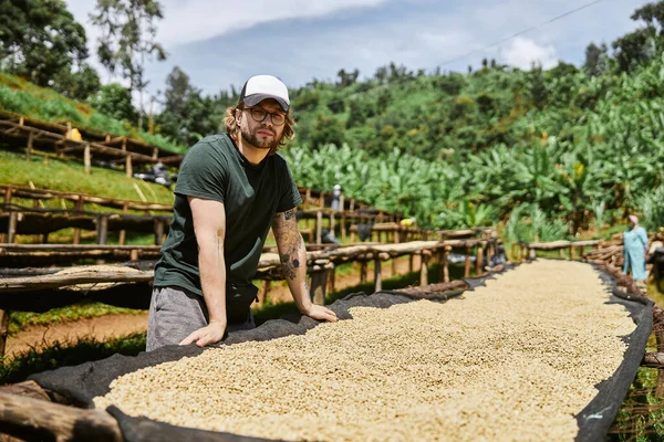 Man in cap standing near coffee washing station in Africa