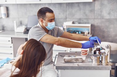 Profesyonel erkek doktor, Stamotoloji kabinesindeki mutlu kadın hastaya anestetik iğne yapmaya hazırlanıyor.