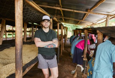 Afrika 'daki kahve yıkama istasyonunda kolları çapraz duran genç adam.