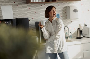 Business woman in casual clothes drinking coffee in office kitchen during break. High quality photo