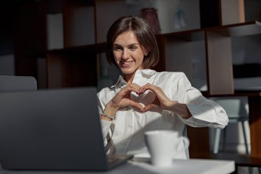 Smiling businesswoman making videocall to friends while working in modern office. High quality photo