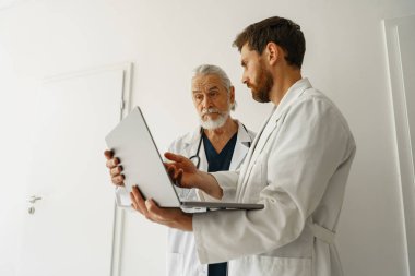 Two doctors are looking at something on the laptop in the doctors office. High quality photo