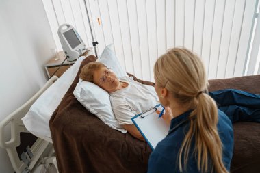 Professional doctor in uniform examines the patient during a visit to hospital ward in clinic