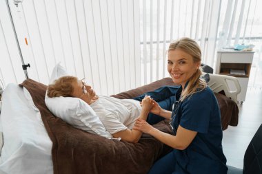 Doctor therapist holding hand of patient in hospital ward and looking camera. High quality photo