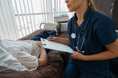 Professional doctor in uniform examines the patient during a visit to hospital ward in clinic