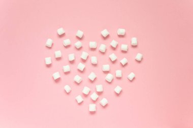 Marshmallow pembe arka planda kalp şeklinde serilmiştir. Aşk kavramı, mutlu sevgililer günü, kadınlar günü ve doğum günü kutlaması. Düzgünce, boşluğu kopyala, taklit et, afiş.