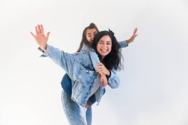 Mutlu kız çocuğu, sırtına gülümseyen anneyi alıyor. Şık bir anne, birlikte eğlenen bir çocuk. İki kadın nesil.