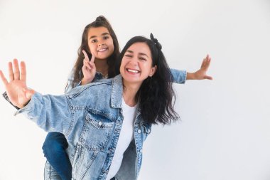 Mutlu kız çocuğu, sırtına gülümseyen anneyi alıyor. Şık bir anne, birlikte eğlenen bir çocuk. İki kadın nesil.