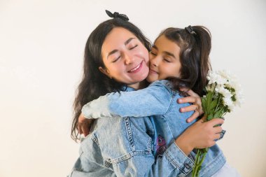 Anneler Günü 'nde küçük kız çocuğundan çiçek alan mutlu bir anne. Anneliğin şefkatli anı.