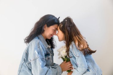 Anneler Günü 'nde küçük kız çocuğundan çiçek alan mutlu bir anne. Anneliğin şefkatli anı.