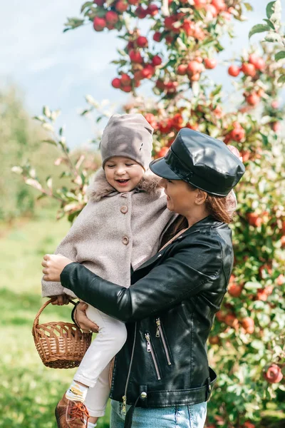 Mamá y su bebé caminando y recogiendo manzanas en el jardín. cosecha otoño. huerto de manzanas, jardín salvaje — Foto de Stock