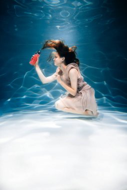 Renkli smoothie ile fitness kızı. Suyun altında tazelik, yüzer ve dalır.
