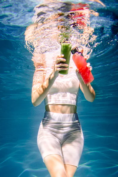 Fitness girl with colorful smoothie. Freshness under water, swims and dives. — Stock Photo, Image