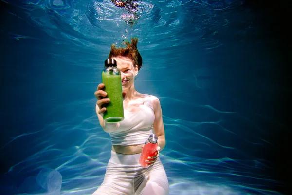 Dziewczyna fitness z kolorowym smoothie. Świeżość pod wodą, pływa i nurkuje. — Zdjęcie stockowe