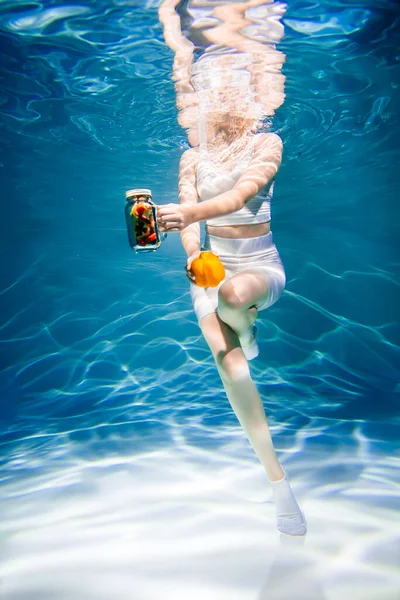 Dziewczyna na niebiesko bez twarzy z warzywami pod wodą, kobieta zdrowe jedzenie koncepcja — Zdjęcie stockowe