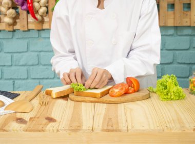 Aşçı üniformalı Asyalı kadın mutfakta yemek pişiriyor.