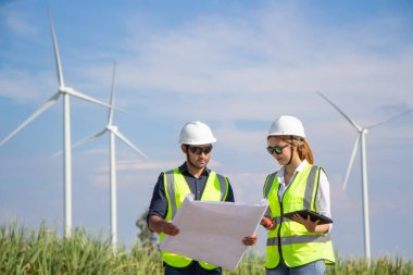 Rüzgar türbini çiftliğinde çalışan mühendis ekibi. Alternatif enerji kavramına göre rüzgar jeneratörüyle yenilenebilir enerji.