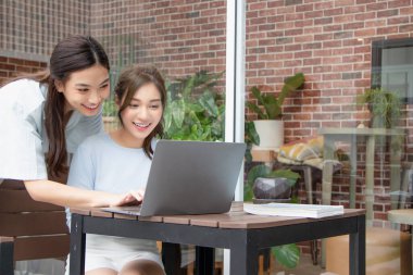 Asyalı kız dışarıda bayan arkadaşıyla çalışırken dizüstü bilgisayarına bakıyor..