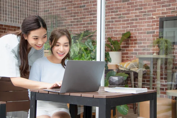 Asyalı kız dışarıda bayan arkadaşıyla çalışırken dizüstü bilgisayarına bakıyor..