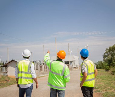 Rüzgar türbini çiftliğinde çalışan mühendis ekibi. Alternatif enerji kavramına göre rüzgar jeneratörüyle yenilenebilir enerji.