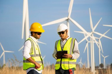 Rüzgar türbini çiftliğinde çalışan mühendis ekibi. Alternatif enerji kavramına göre rüzgar jeneratörüyle yenilenebilir enerji.