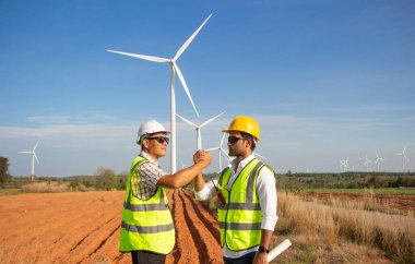 Rüzgar türbini çiftliğinde çalışan mühendis ekibi. Alternatif enerji kavramına göre rüzgar jeneratörüyle yenilenebilir enerji.