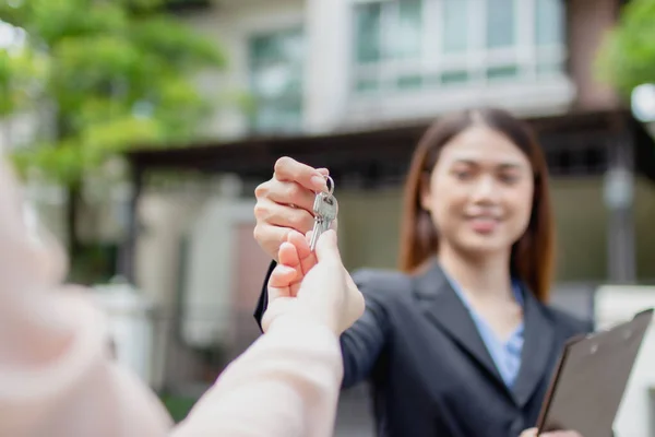 Young asian woman holding the key with new house. Real Estate Agent giving house keys