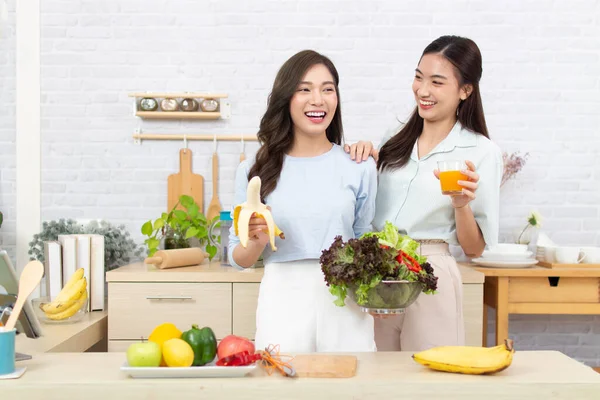 Asian two women wearing  sportswear eat healthy foods in kitchen