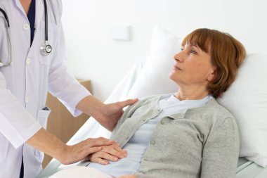 Doktor, hastanedeki hastayı muayene ediyor. Beyaz erkek doktor yaşlı beyaz bir hastayı muayene ediyor..