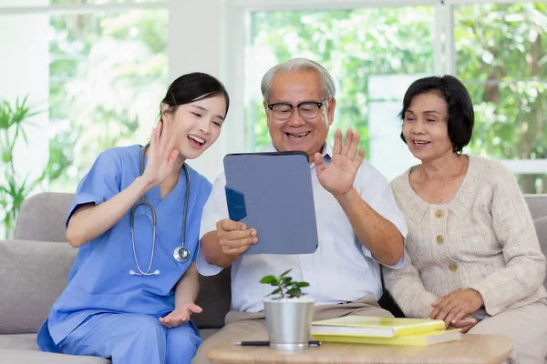 Nursing Home Care concept. Beautiful Asian nurse and elderly person using tablet video call online Chatting with family while in nursing home.