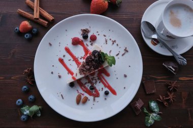 Nane ve kırmızı şurupla süslenmiş bir tabakta ahududu peynirli kek.