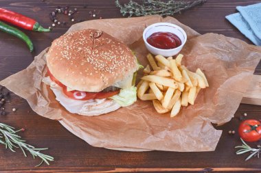Patates kızartmalı hamburger ve ahşap üzerine baharatla süslenmiş sos.