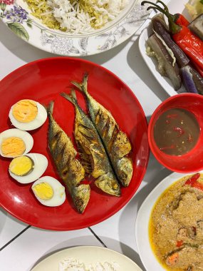 Yanında haşlanmış sebze, haşlanmış yumurta, kızarmış balık ve pilav..