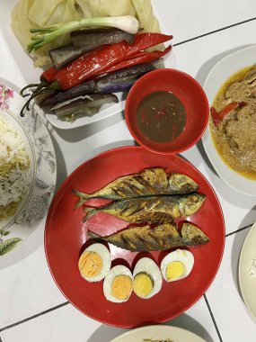 Yanında haşlanmış sebze, haşlanmış yumurta, kızarmış balık ve pilav..