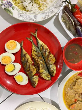 Yanında haşlanmış sebze, haşlanmış yumurta, kızarmış balık ve pilav..