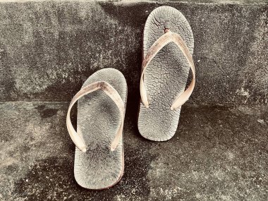 Kirli arka planda eski terlikleri kapat