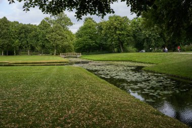    Schwerin, Almanya - 20 Temmuz 2021 - Bulutlu yaz akşamında heykelleri ve küçük köprüleri olan Castle Garden                            