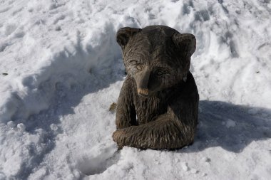 Güneşli bir kış gününde popüler bir dağ beldesinde yüksek katmanlı karla kaplı bir ayının el oyması figürü.                                 