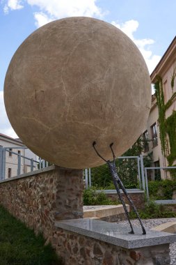 Rakovnik, Çek Cumhuriyeti - 2 Temmuz 2022 - Güneşli bir yaz öğleden sonrasında bir adamın heykeli dağ yamacında ağır bir taş yuvarlıyor.                               