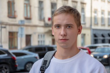 20-25 yaşlarındaki gülümseyen bir gencin sokak portresi omzunda sırt çantasıyla eski şehir mimarisinin arka planına yaslanmış. Belki de bilişim uzmanıdır ya da turist, öğrenci ya da acemi bir uzmandır..