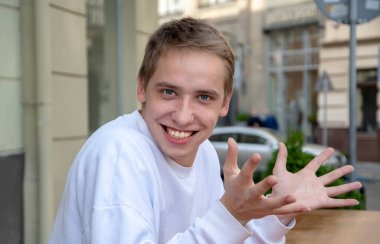 Yazın sokakta kollarını açmış genç bir adamın duygusal portresi..