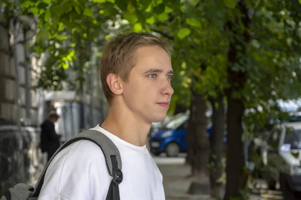 20-25 yaşlarındaki gülümseyen bir gencin sokak portresi omzunda sırt çantasıyla eski şehir mimarisinin arka planına yaslanmış. Belki de bilişim uzmanıdır ya da bir turist, ya da bir öğrenci. 