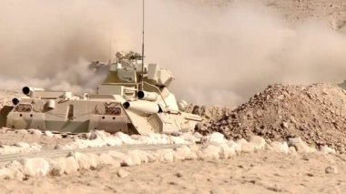 Zırhlı askerlerle dolu zırhlı araçlar çölde askeri teçhizatların yanından geçiyor, seçici bir odak noktası. Kavram: askeri çatışma bölgesinde bir savaş grubu.