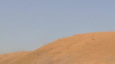 Bir savaş helikopteri çöldeki bir dağın arkasından havalanıyor. Kavram: Havadan saldırı ve keşif, askeri çatışma bölgesinde savaş operasyonları.