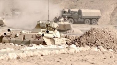 Zırhlı askerlerle dolu zırhlı araçlar çölde askeri teçhizatların yanından geçiyor, seçici bir odak noktası. Kavram: askeri çatışma bölgesinde bir savaş grubu.