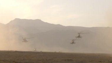 Askeri helikopterlerden oluşan bir muharebe birimi çölün üzerinden uçup dağlara iniyor. Kavram: Havadan saldırı ve keşif, askeri çatışma bölgesinde savaş operasyonları.
