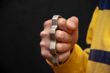 Erkek eli siyah arka planda metal muştayı sıkar. Kavram: ağır yaralanmalar, sokak kavgaları, kuralsız kavgalar, kentsel suçlar.
