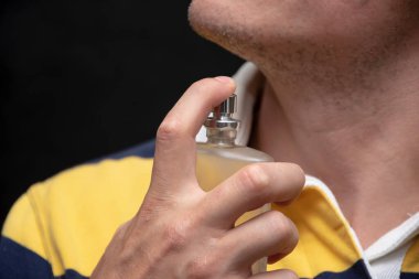 Bir adam şişeden kendine parfüm sıkar, yakın plan. Konsept: Pahalı koku, randevuya çıkmak, hoş koku ve güzel koku..