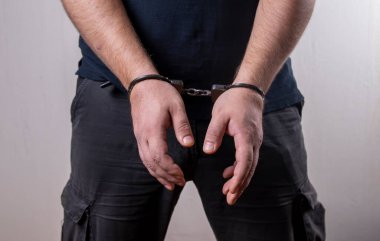 A man handcuffed on a light background. Concept: a detained criminal, an illegal migrant in a police station, a border violator, a bribe taker and a corrupt official, arrest clipart